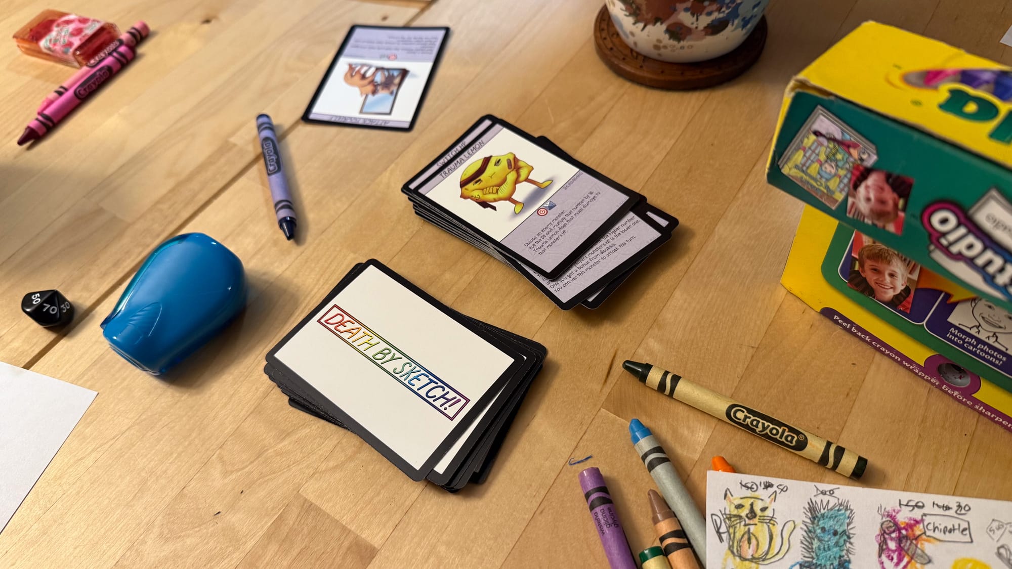 A photo of a table with Death By Sketch cards, crayons, and other drawing tools.