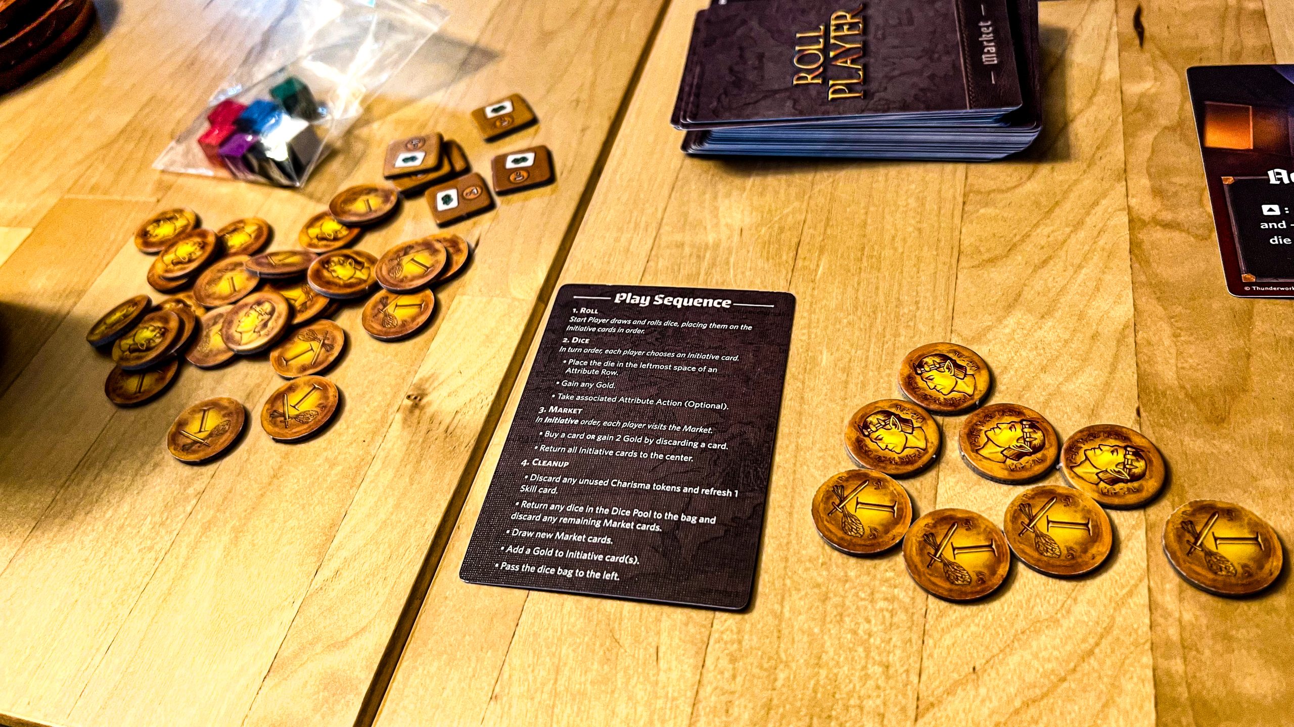 A photo showing gold tokens and a rule summary card for Roll Player