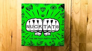 The box art of Nuck Tats, a card game. Shows two fists with the name Nuck Tats written on the fists