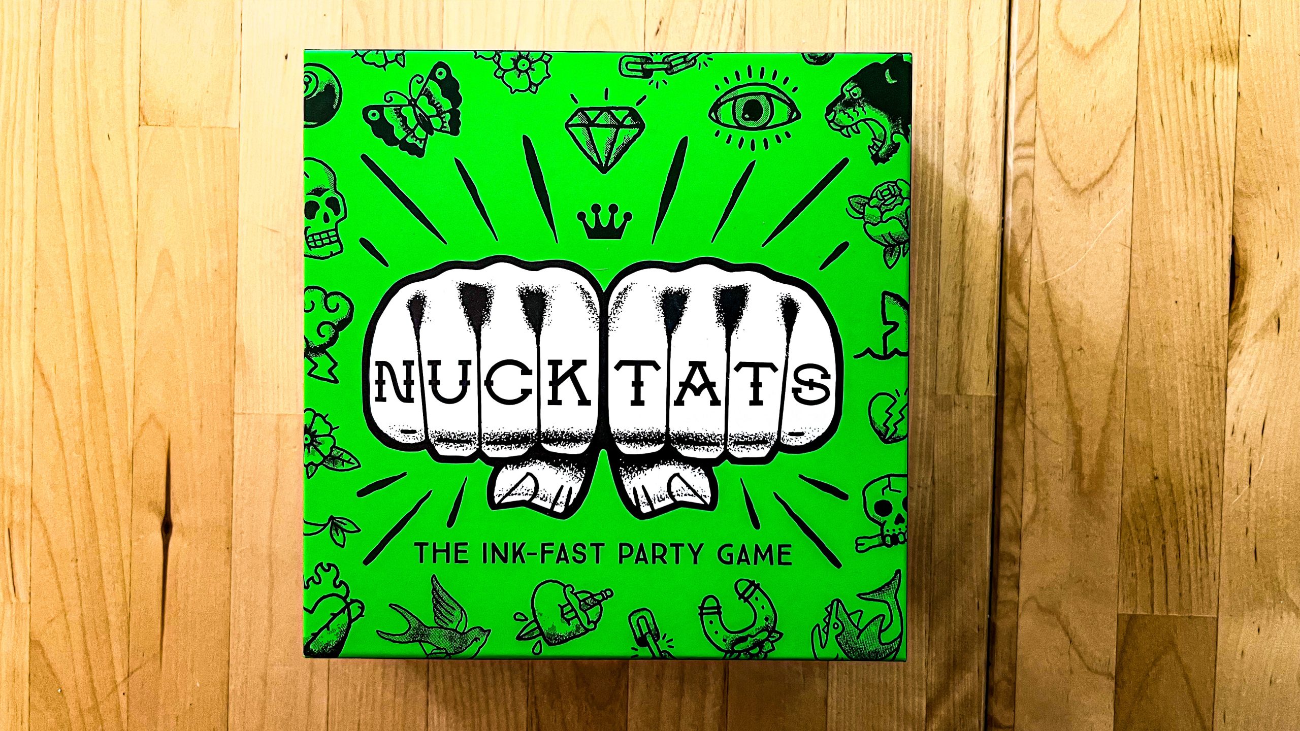 The box art of Nuck Tats, a card game. Shows two fists with the name Nuck Tats written on the fists